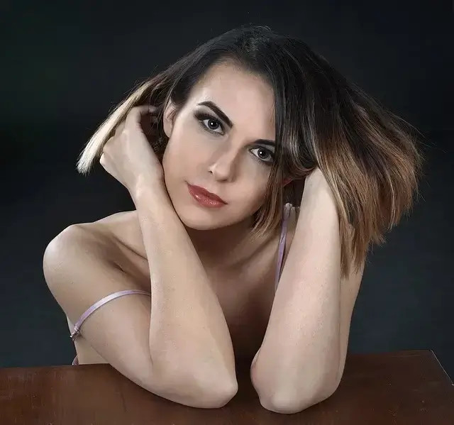 Mujer con cabello castaño, recostada sobre una mesa, mirando a cámara con expresión serena. Cutis Graso.